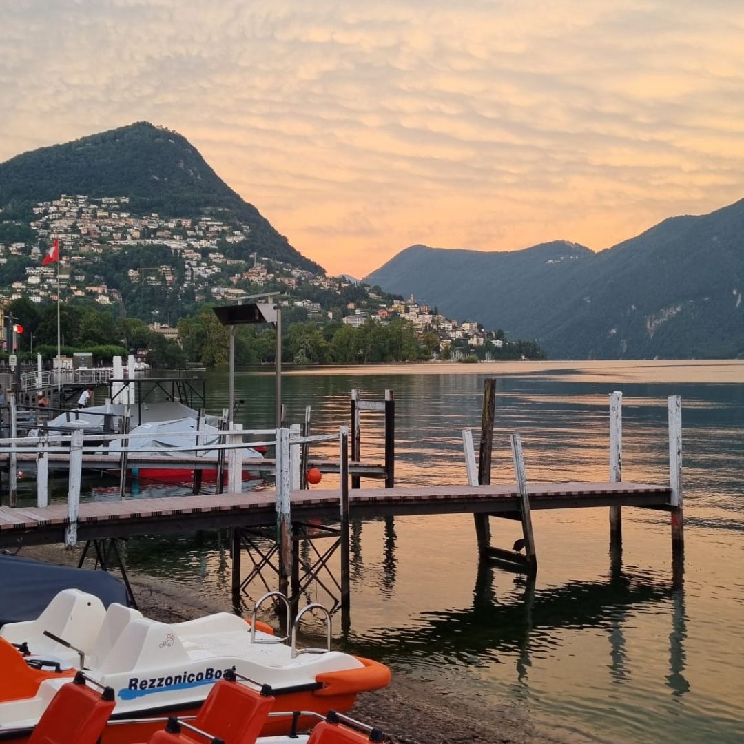 der luganer see bei sonnenuntergang, perfekt zum schwimmen mit hunden, boote und steg